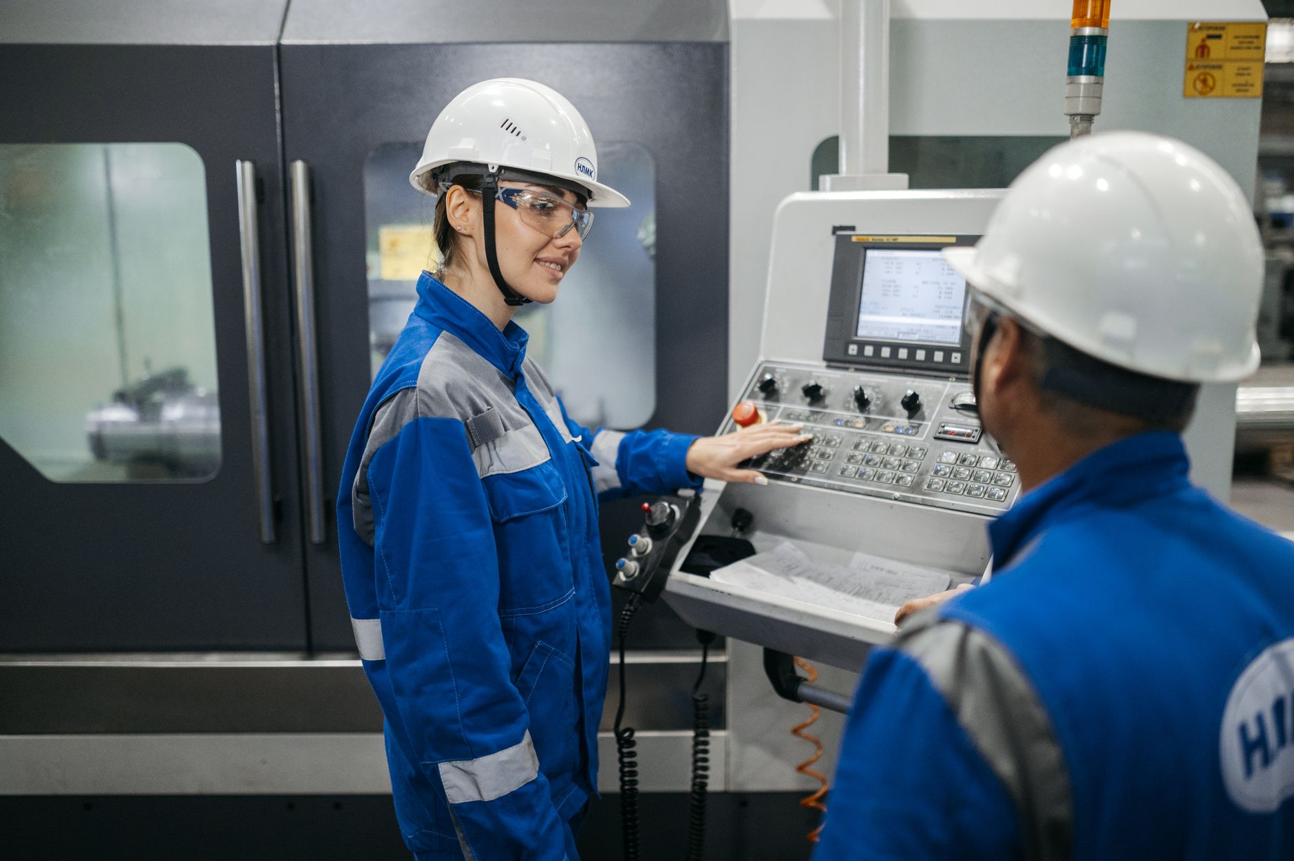 Automation engineers reviewing PLC code together at a workstation in an industrial control room