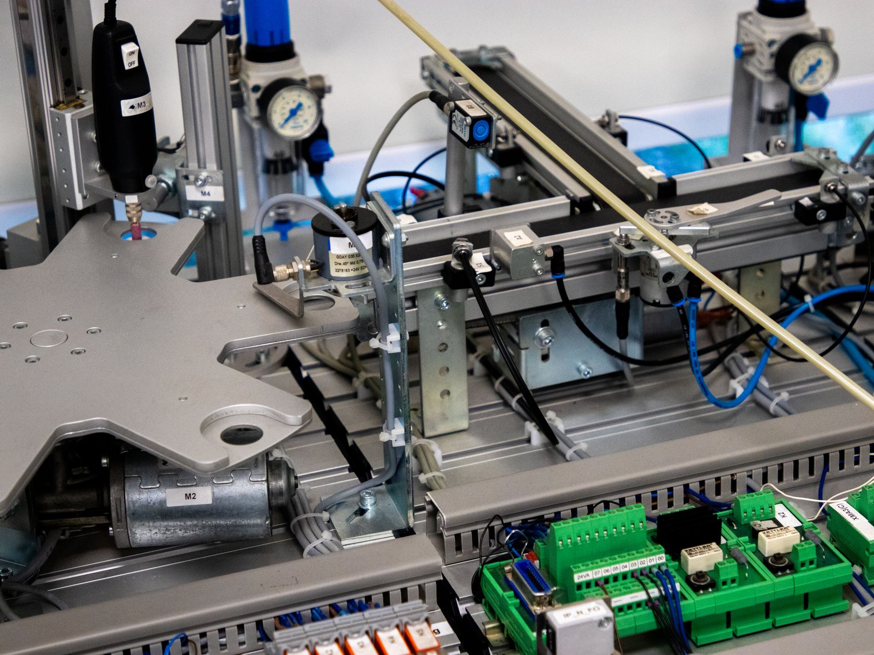 Collaborative robot arm working near a servo-driven conveyor with safety light curtain in an industrial cell