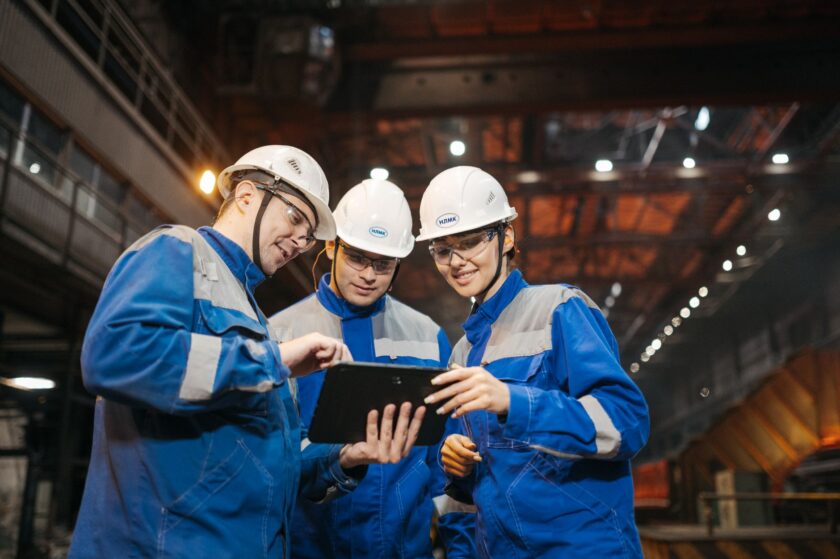 Maintenance technician reviewing a work order on a tablet next to industrial equipment