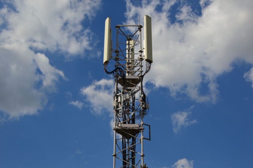 Private 5G antenna mounted on a warehouse ceiling above an AMR moving through a manufacturing aisle