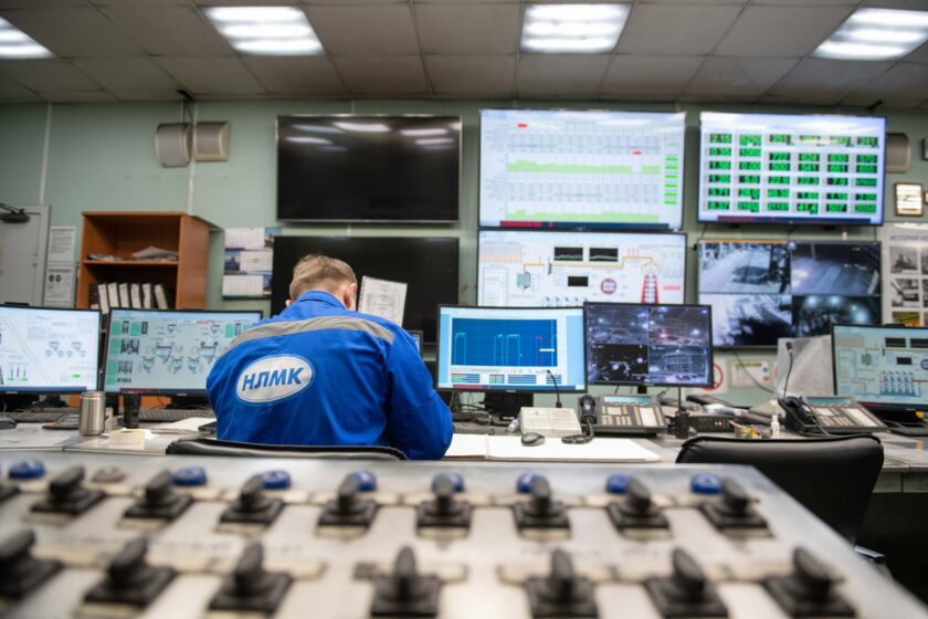 Plant operator viewing MES dashboards on multiple screens in a manufacturing control room