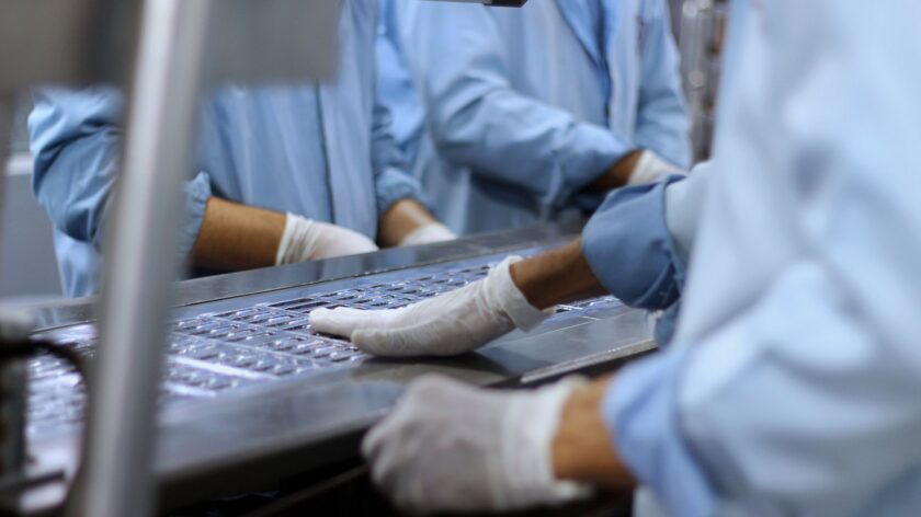 Manufacturing worker reviewing lot and batch records on a screen in a production facility