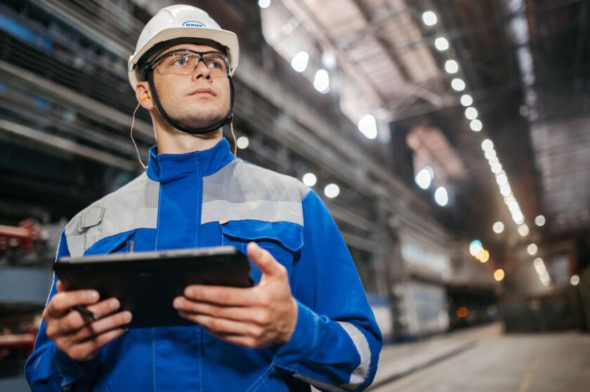 Manufacturing worker recording quality data on a tablet at a shop-floor workstation