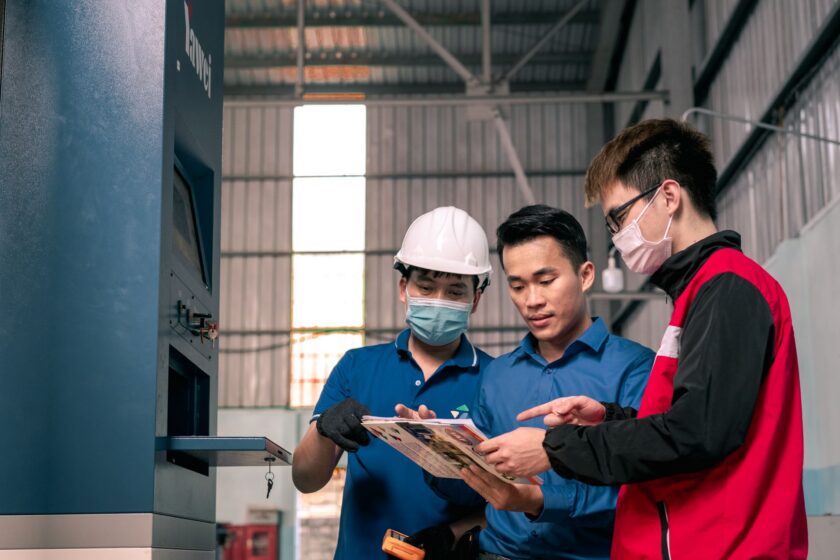 Operators reviewing a digital dashboard during a shift change on a factory floor