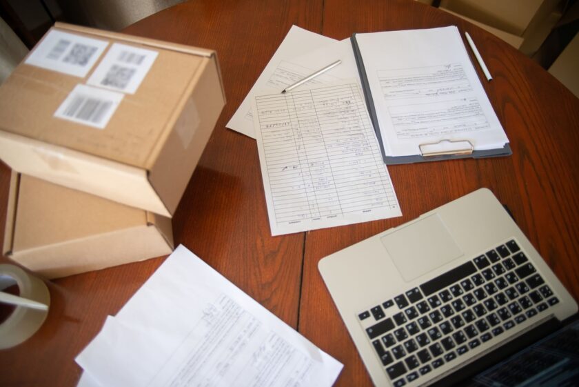 A work order document on a clipboard next to a factory production line