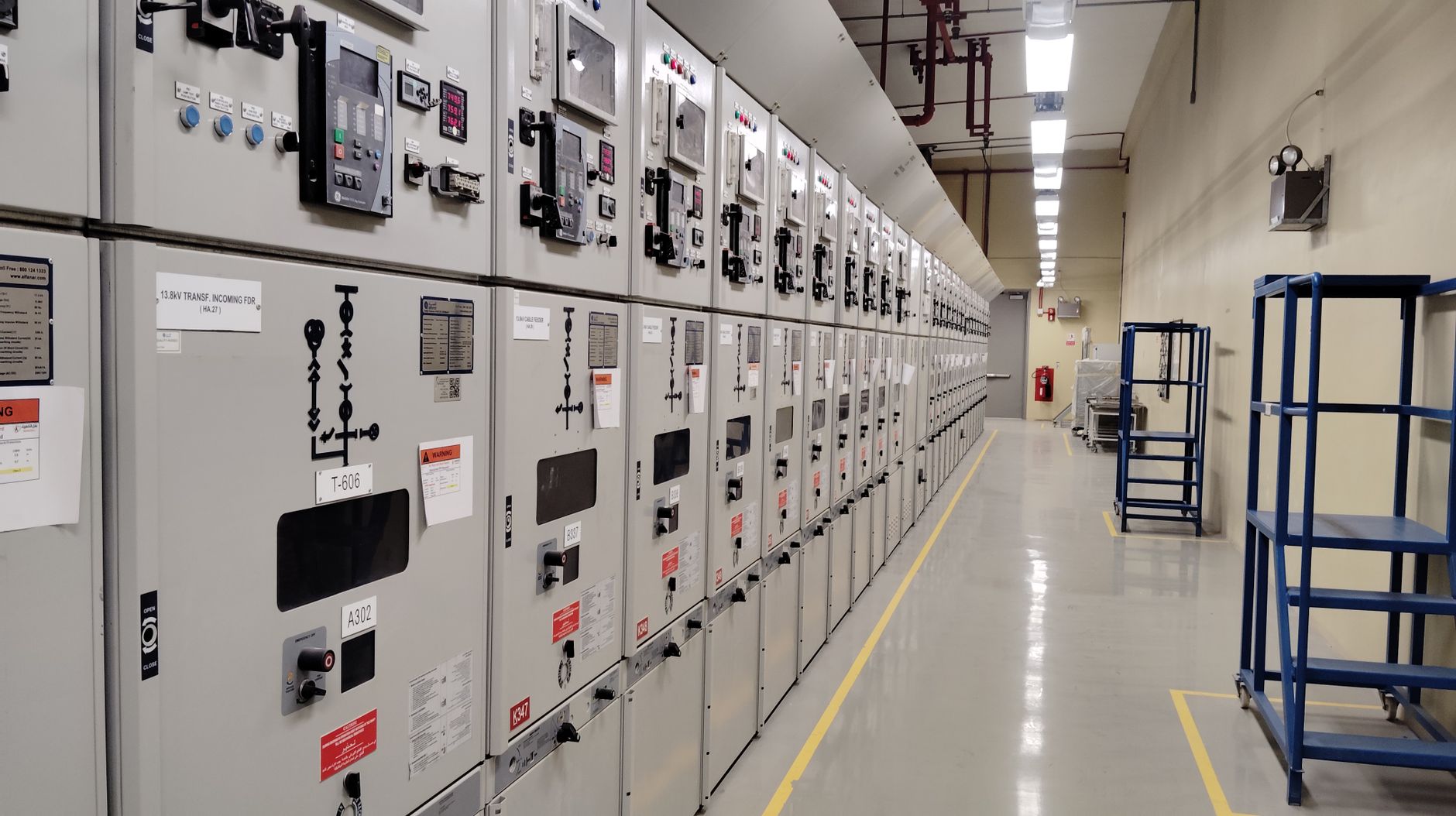 Technician standing before an industrial control panel with PLC and RTU hardware in a manufacturing plant
