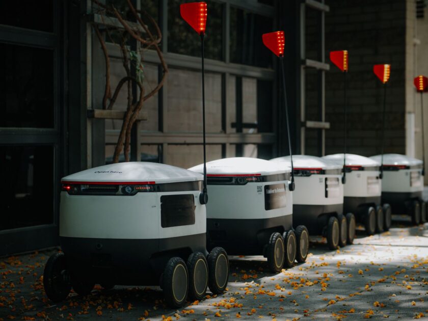Multiple autonomous mobile robots from different manufacturers moving through a warehouse aisle