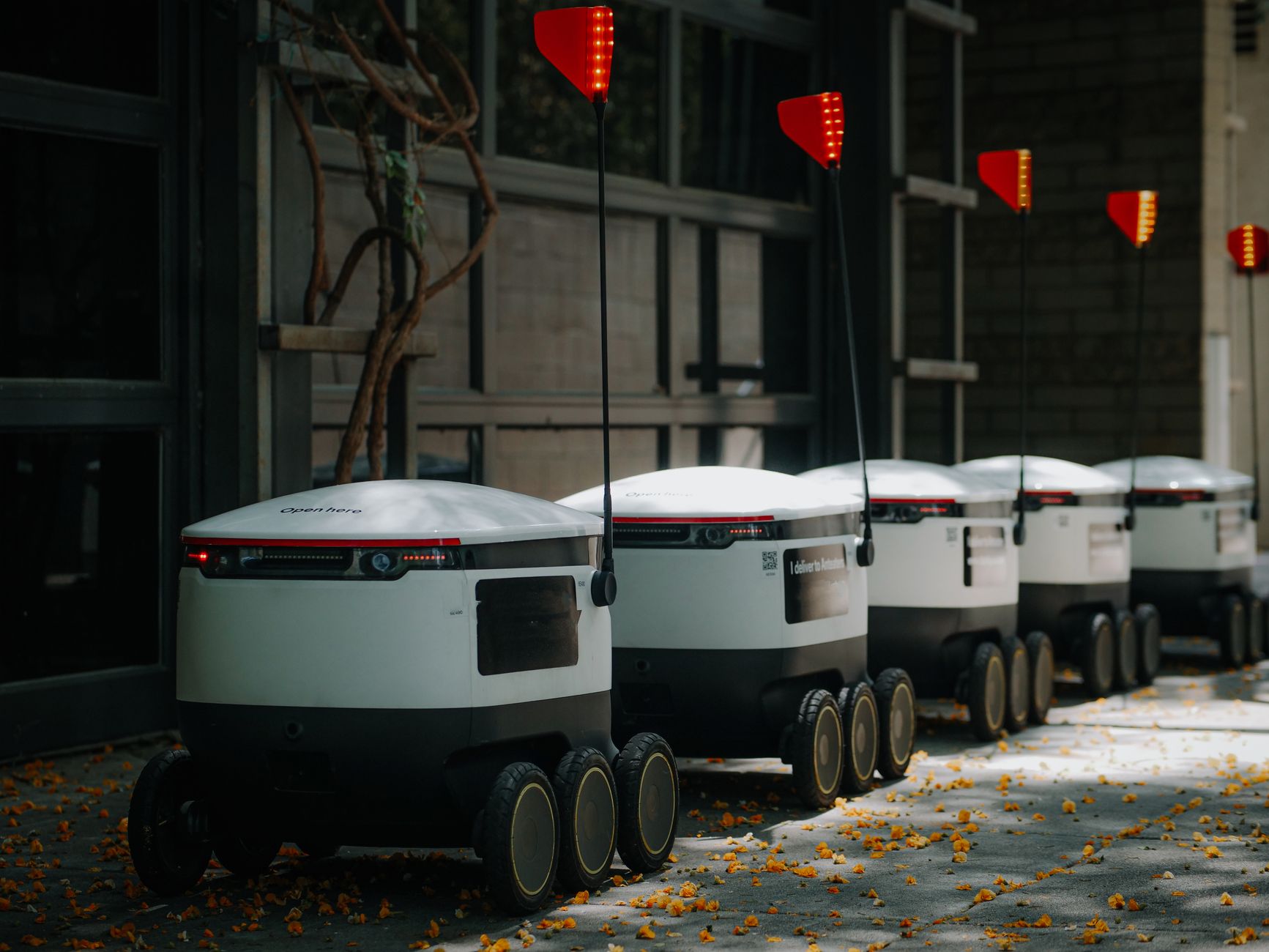 Multiple autonomous mobile robots from different manufacturers moving through a warehouse aisle